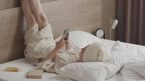 Woman Relaxing in Bed Checking Smartphone