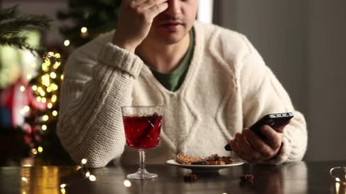 Man Using Phone with Christmas Decorations Indoors