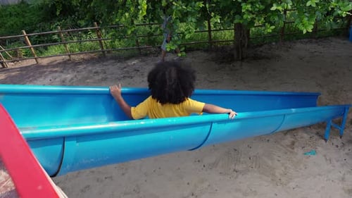 4K Little African girl sliding and playing at playground in the park