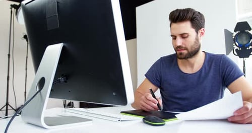 Young Man Designs with Computer in Photography Studio