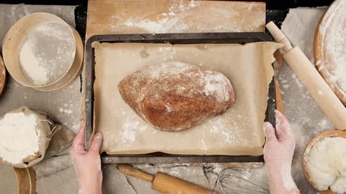Zwei weibliche Hände legten eine Metallpfanne mit gebackenem Brot auf den Tisch.