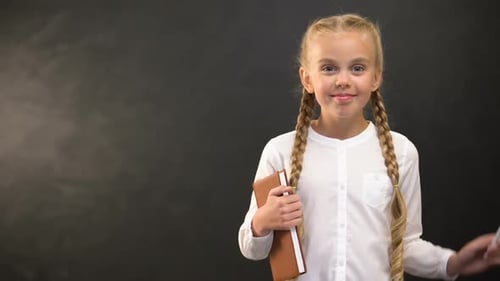 Smiling Girl Holding Book and Chalk in School