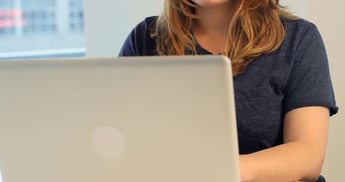 Woman Typing on Laptop in Bright Office Setting