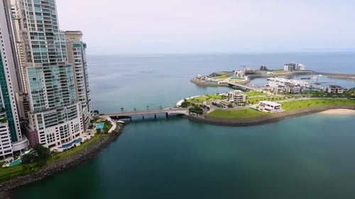 Aerial drone footage of artificial island in front of buildings in Panama City
