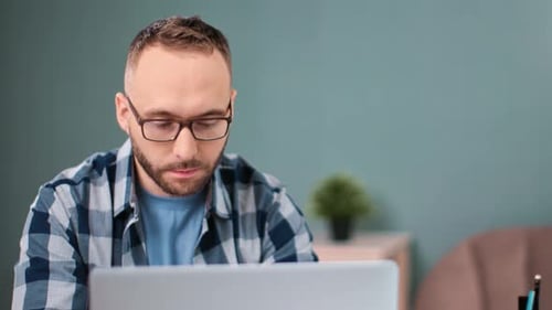 Man Works on Laptop at Desk