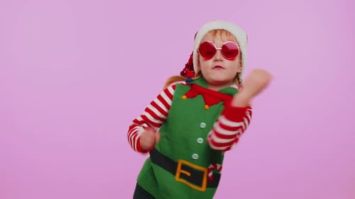 Child Dances in Elf Costume Against Pink Background
