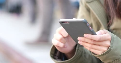 Woman Uses Smartphone in Urban Setting During Day