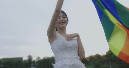 Woman Waving Rainbow Flag in Park Setting