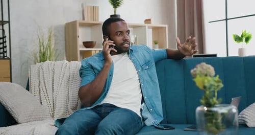 Man Talking on Phone, Sitting on Couch Indoors