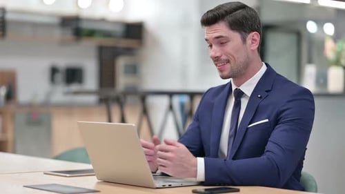 Cheerful Businessman Talking on Video Call on Laptop in Office