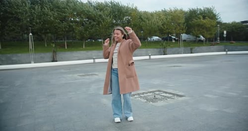 Young Woman Listens to Music and Dances on Empty Road
