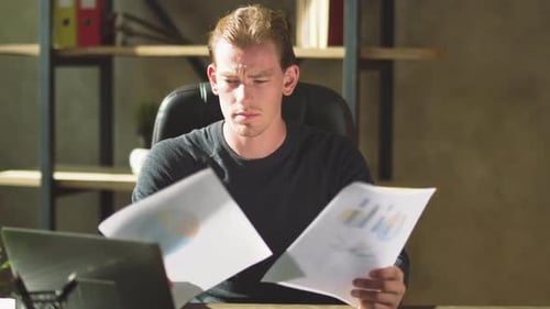 Thoughtful Businessman Sitting at the Office Desk and Working with Documents in the Workplace