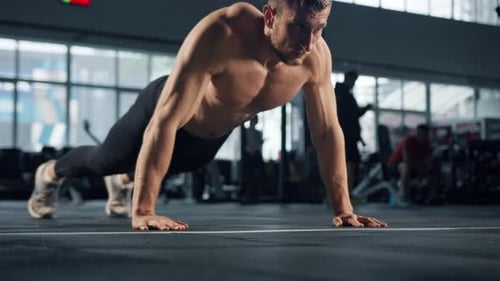 Young male athlete trains in the gym, push-ups from the floor, crossfit, endurance training