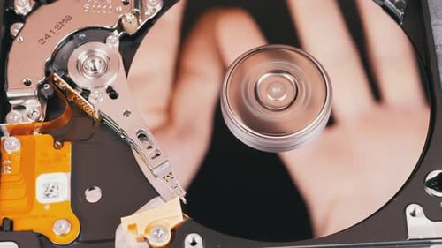 Festplattenlaufwerk innen. Reflexion von Handflächen auf der Spiegelfläche einer Magnetplatte