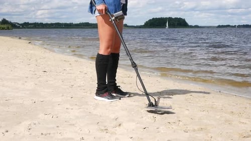 Woman Searching with Metal Detector on Beach