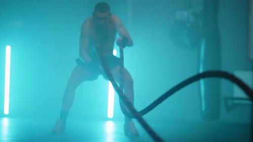 Muscular Man Doing Rope Exercises in Gym