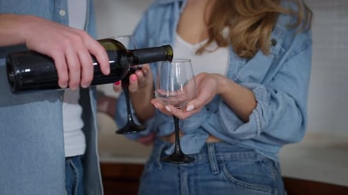 Nahaufnahme Männliche Hand gießt Rotwein in zwei Gläsern in weiblichen Händen