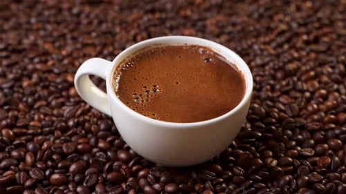Side View of White Cup of Black Coffe on Coffee Beans