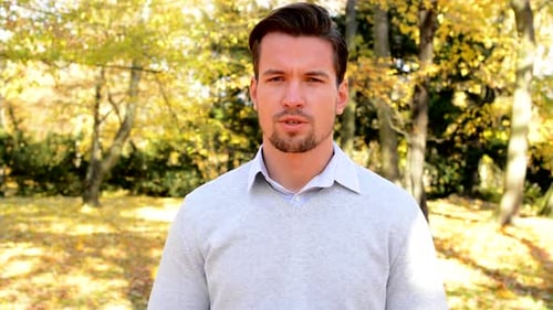 Un jeune homme se tient dans les bois et parle de quelque chose