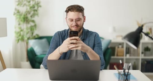 Man Using Cellphone While Sitting at Desk