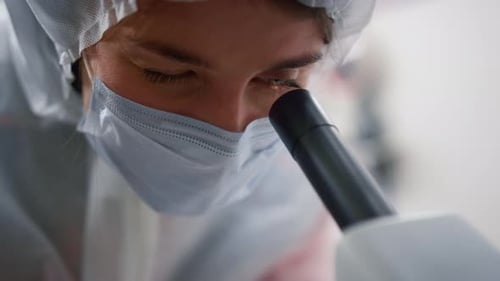 Scientist Looking Through Microscope in Laboratory