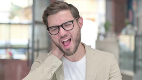 Young Adult Male Rubbing Stiff Neck in Office