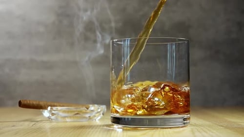 Whiskey Poured into Glass with Ice and Cigar