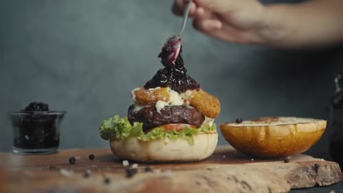 Delicious Burger Being Dressed with Dark Sauce
