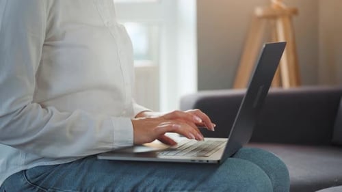 Close-up Woman Working on a Laptop Against the Sunset. Concept of Remote Work.