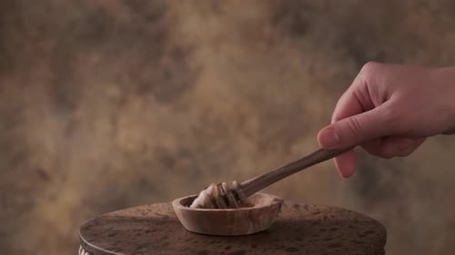 Honey Dipper Drizzling Golden Honey into a Bowl