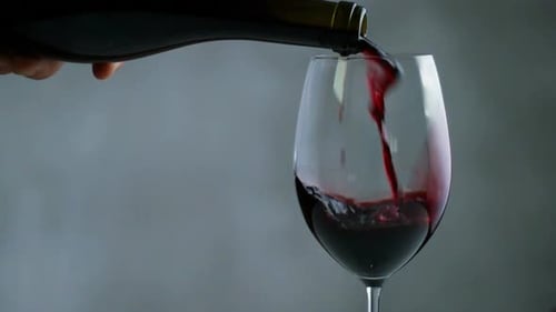 Vinho tinto derramando na taça de vinho. Fechar acima. Vídeo Cinemagraph de loop contínuo