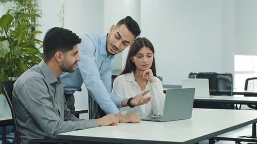 Office Colleagues Collaborating Around Laptop in Modern Workspace