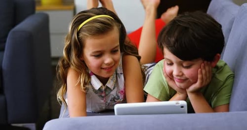 Brother and Sister Enjoying a Tablet on the Couch