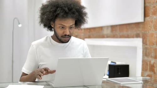 Frustrated Man Working on Laptop at Desk