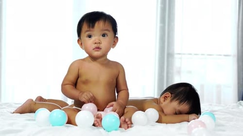 Baby Plays While Sibling Sleeps Peacefully