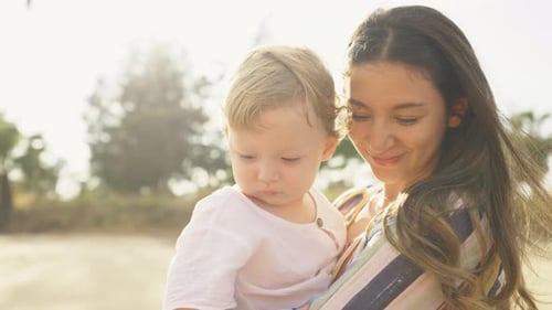 4K Caucasian mother carrying baby son walking on tropical beach in summer sunny day