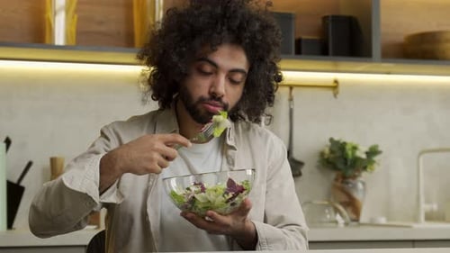 Young Adult Eating a Salad in a Kitchen