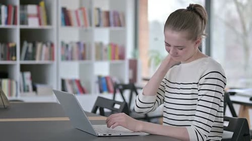 Laptop Use By Young Woman with Neck Pain in Library