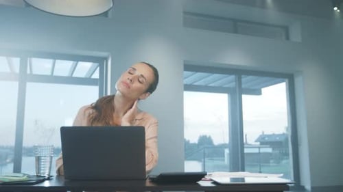 Businesswoman Stretches Neck Working from Home