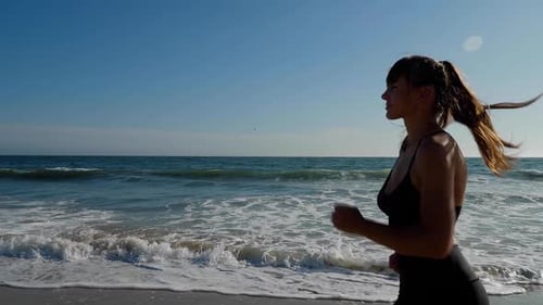 Athletic woman jogging along the beach