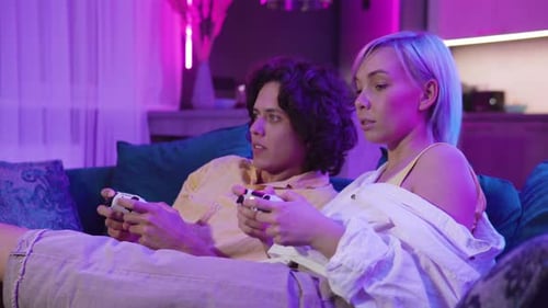 Couple Playing Video Games on Sofa at Night