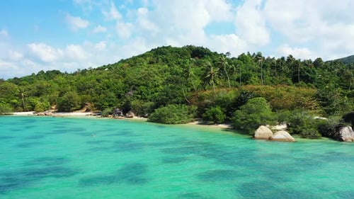 Blue turquoise lagoon washing private exotic beach hidden by lush vegetation and big limestone cliff