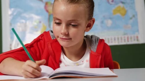 Schoolgirl doing homework in classroom at school