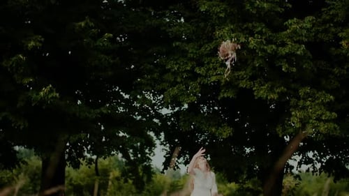 Woman Throws Wedding Bouquet in Lush Green Field