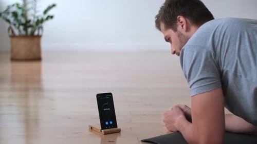 Man Doing Plank Exercise with Timer at Home