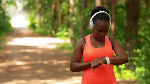 Woman Checks Smartwatch while Jogging in Forest