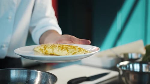 Professional restaurant kitchen, close-up: The chef serves an omelette