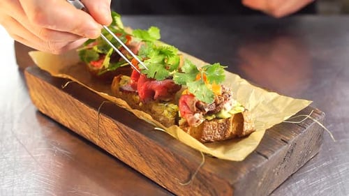 Chef Is Finishing Meal Teasty Beef Steak with Salad for Guest of Restaurant. Final Touch Basil Leaf.