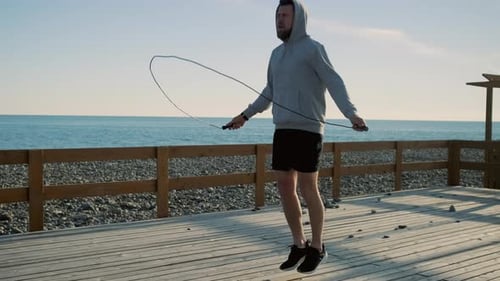 Athletic Man Jumps Rope on Beachfront Deck