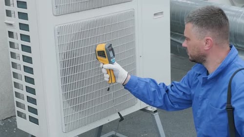Technician Inspecting Air Conditioning Unit With Thermal Imager